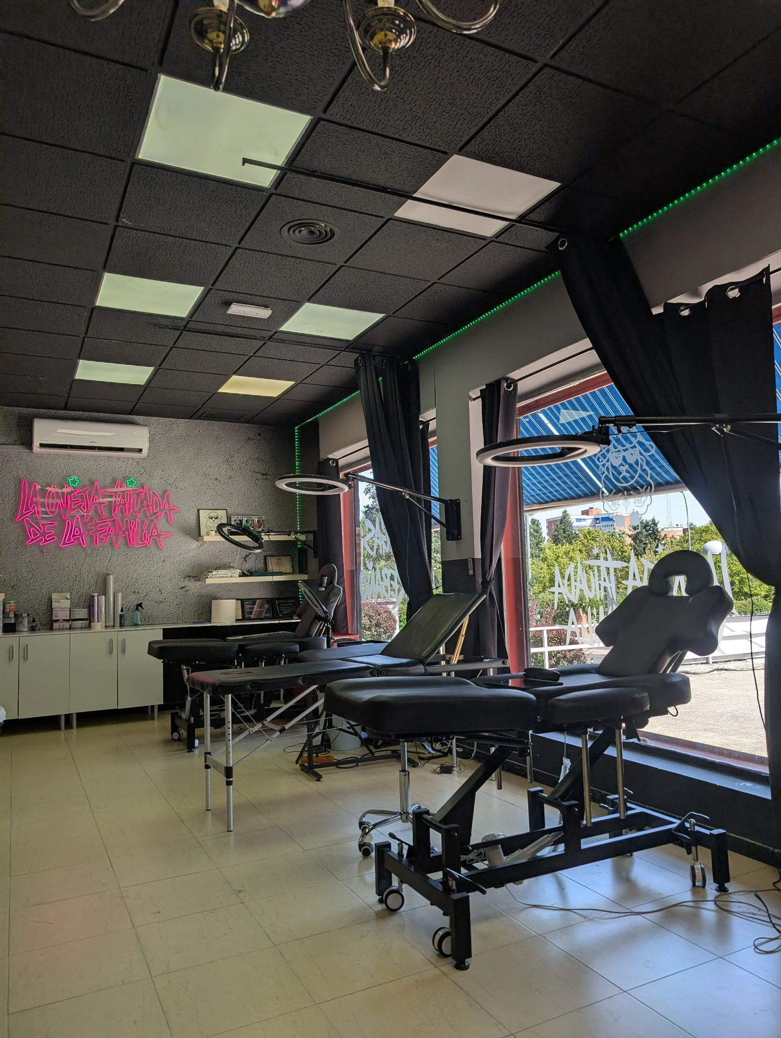 Zona de tatuaje junto a fachada y neón decorativo en el estudio.